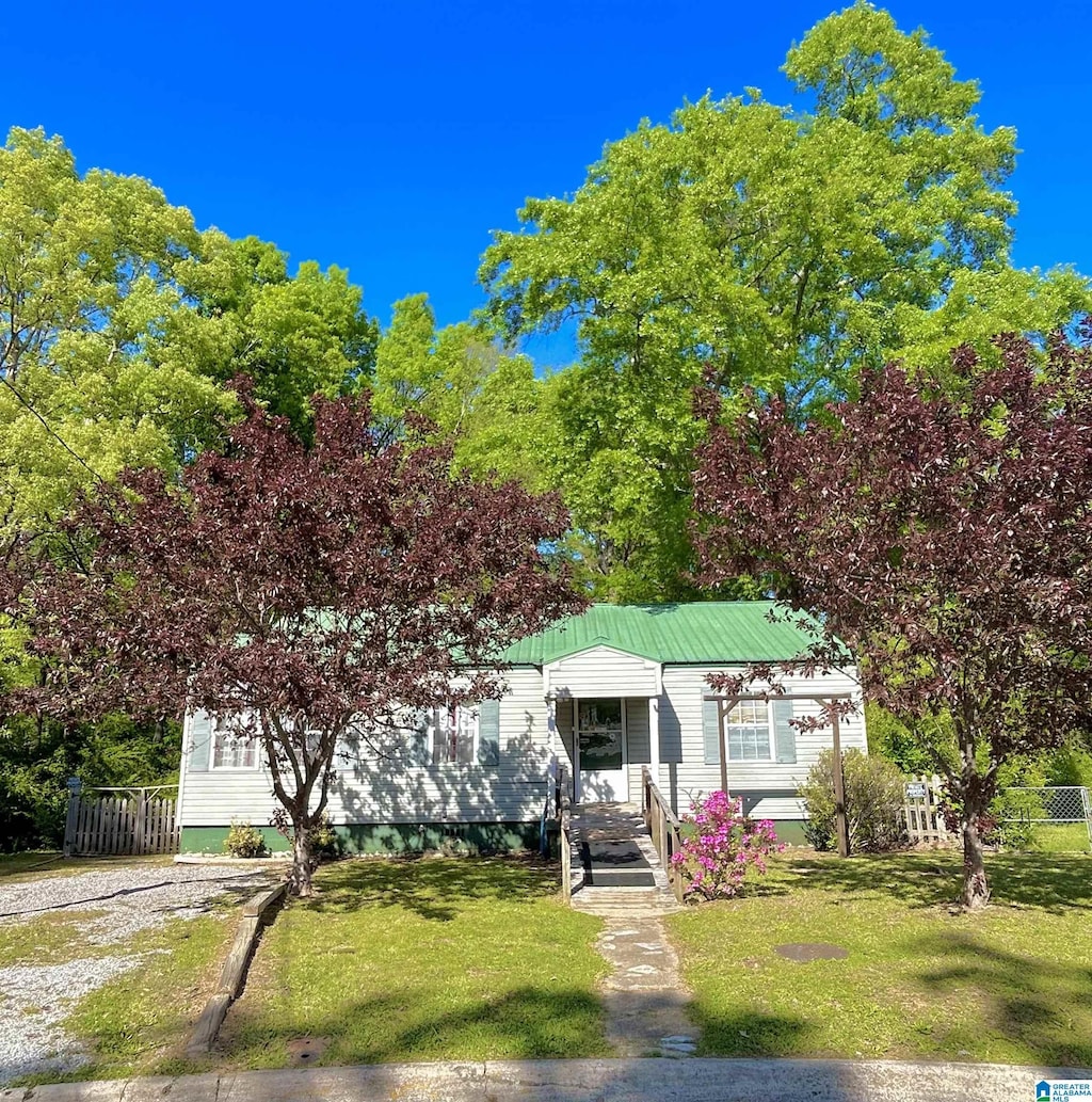view of front of home featuring fence, metal roof, a front yard, and dirt driveway