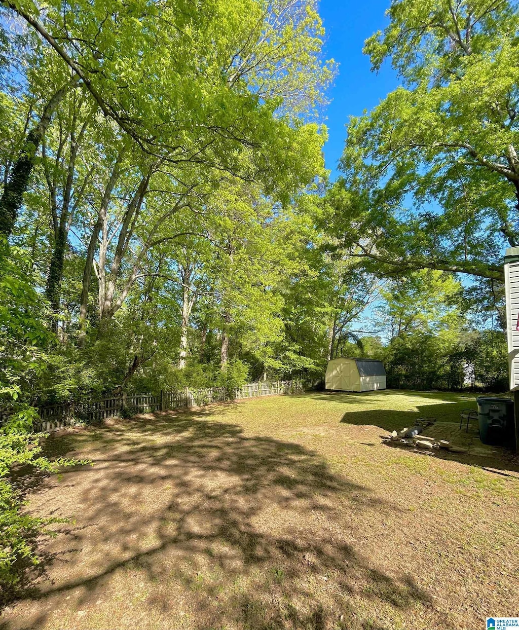 view of yard featuring fence, a shed, and an outbuilding