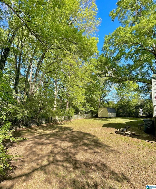 view of yard featuring fence, a shed, and an outbuilding