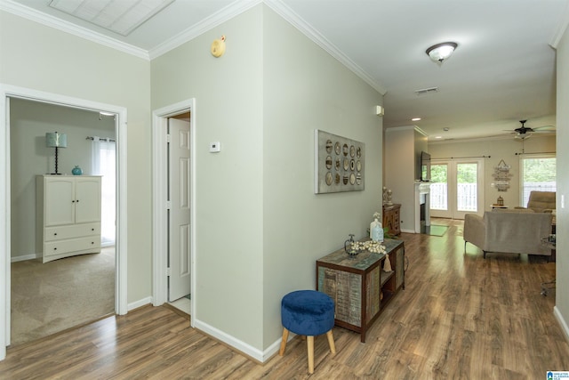 corridor with baseboards, ornamental molding, wood finished floors, and visible vents