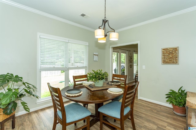 dining space featuring visible vents, light wood-type flooring, baseboards, an inviting chandelier, and ornamental molding