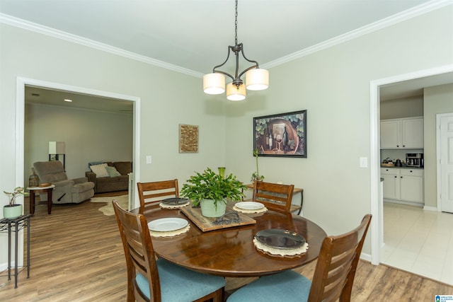 dining area featuring crown molding, baseboards, a chandelier, and light wood-style floors