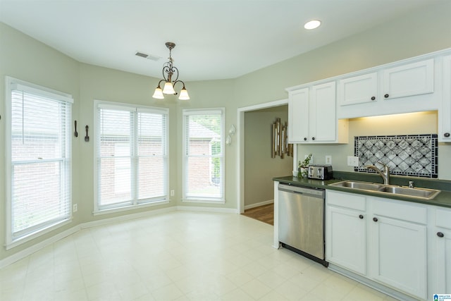 kitchen featuring visible vents, dark countertops, stainless steel dishwasher, a sink, and white cabinets
