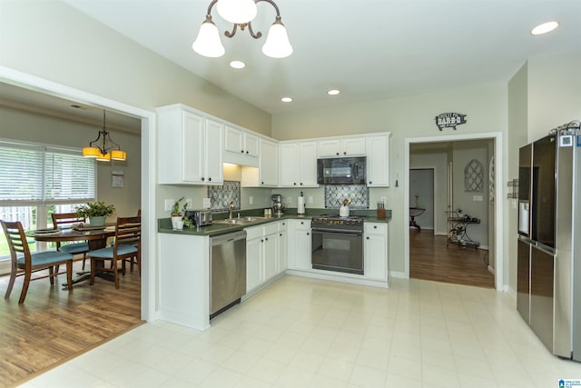 kitchen featuring dark countertops, a sink, white cabinets, black appliances, and recessed lighting