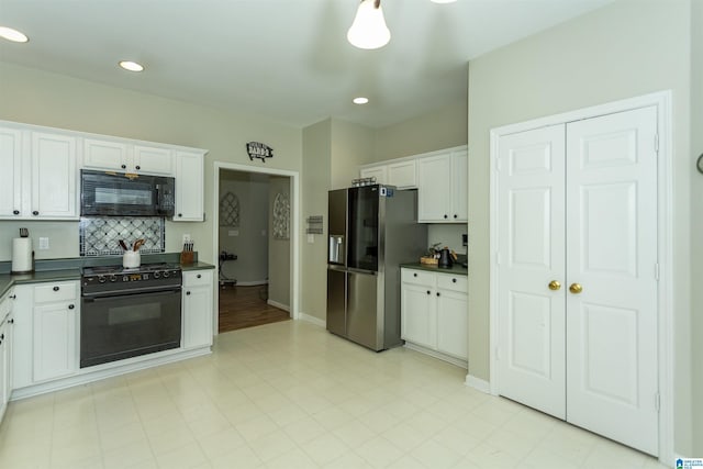 kitchen featuring dark countertops, baseboards, black appliances, and white cabinetry