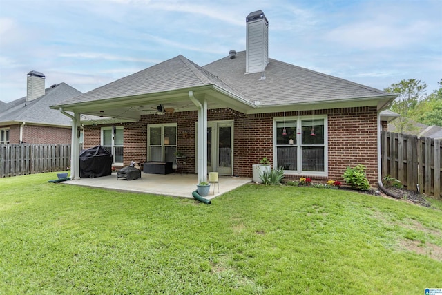 rear view of property with a fenced backyard, ceiling fan, a yard, and brick siding
