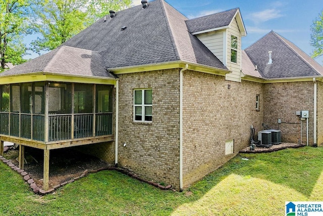 view of home's exterior with a sunroom, a shingled roof, a yard, and brick siding