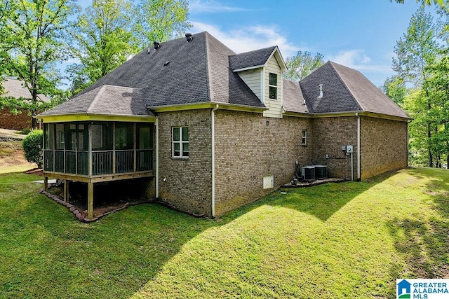back of property with a lawn, a sunroom, roof with shingles, and brick siding