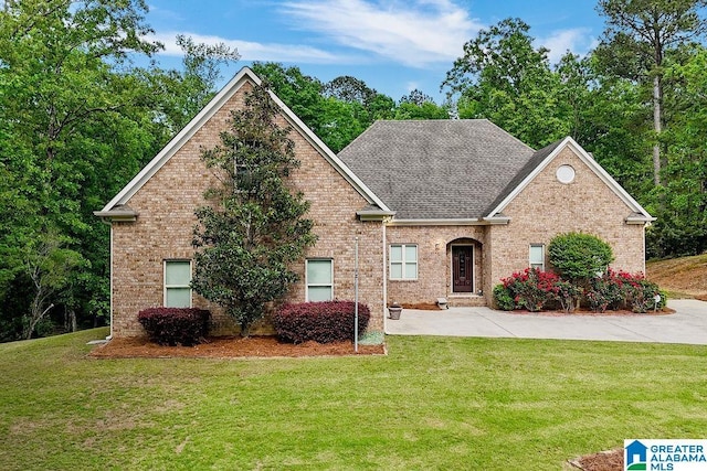 view of front of home featuring brick siding, a shingled roof, and a front lawn