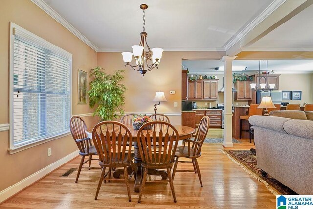 dining space featuring an inviting chandelier, crown molding, light wood-style floors, and decorative columns