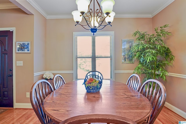 dining space with baseboards, an inviting chandelier, ornamental molding, and light wood-style flooring