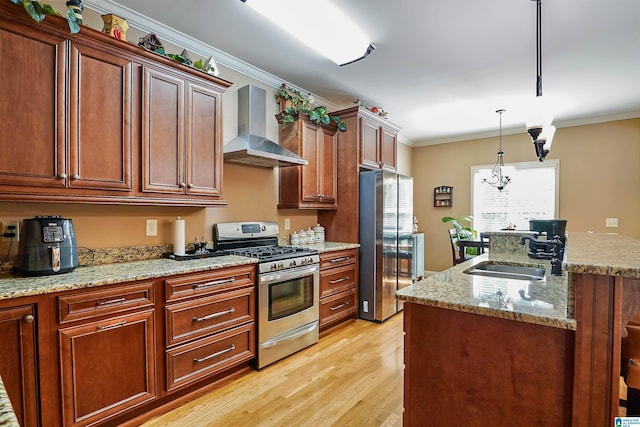kitchen featuring wall chimney range hood, crown molding, a sink, light wood finished floors, and stainless steel appliances