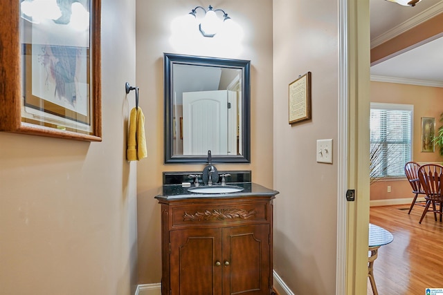 bathroom featuring crown molding, baseboards, wood finished floors, and vanity