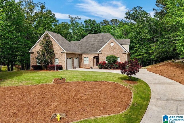 traditional home with driveway, roof with shingles, a front yard, a garage, and brick siding