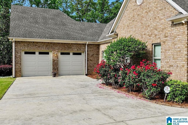 view of front of house featuring a garage, a shingled roof, concrete driveway, and brick siding