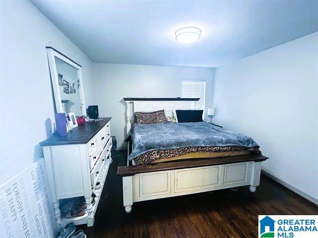 bedroom with dark wood-type flooring and baseboards