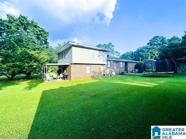 rear view of house featuring a yard and a trampoline