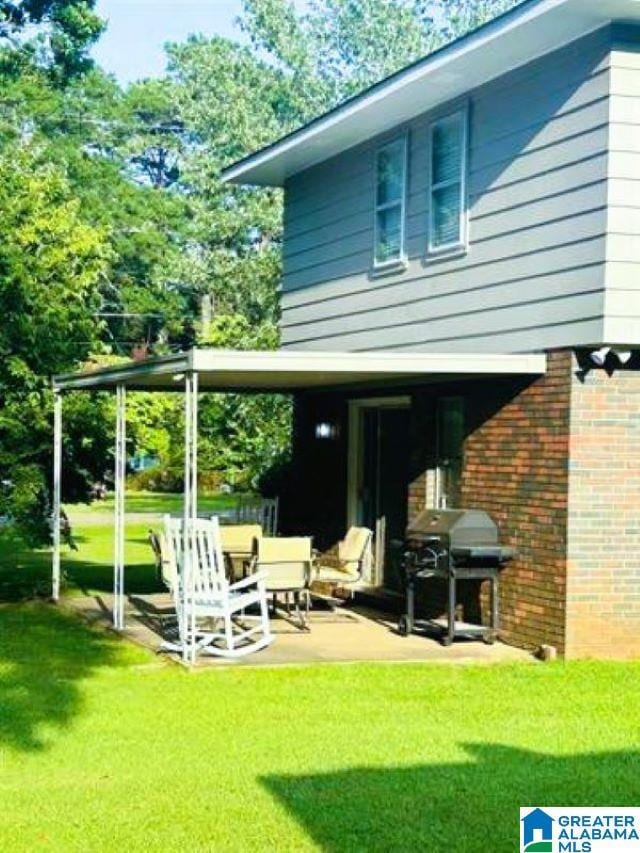 rear view of house with a lawn, a patio, and brick siding