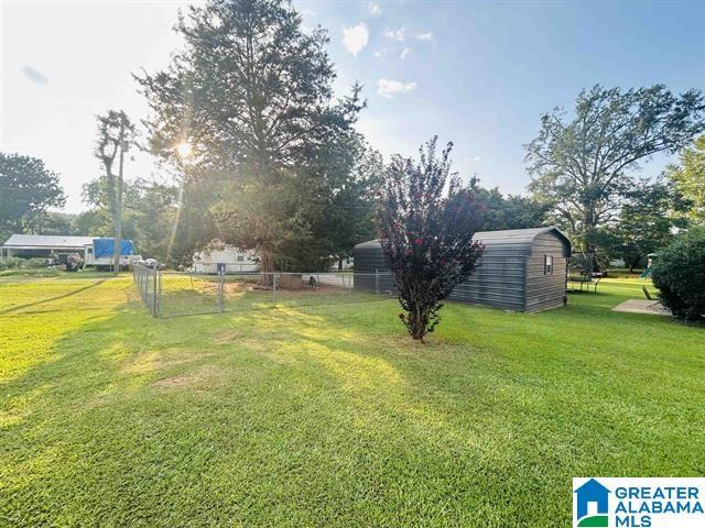 view of yard featuring fence, a storage shed, and an outdoor structure