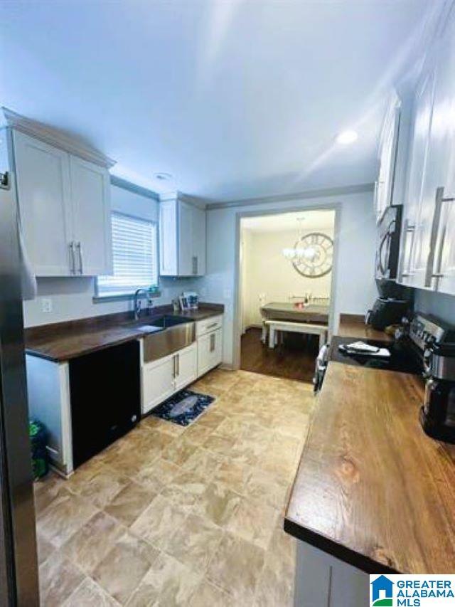 kitchen with dark countertops, a chandelier, stainless steel microwave, and a sink