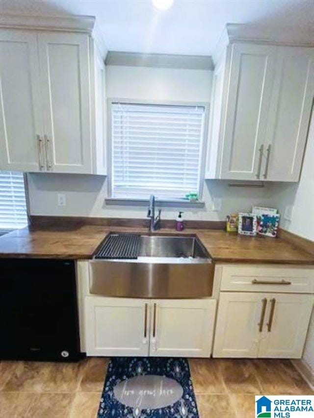 kitchen with wooden counters, a sink, and white cabinetry