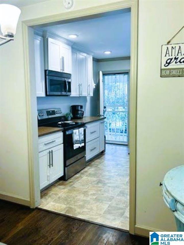 kitchen with white cabinetry, stainless steel appliances, dark countertops, and light wood finished floors