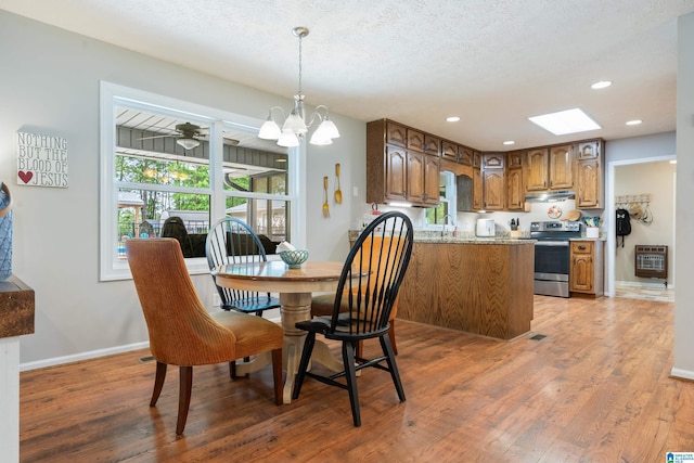 dining area with heating unit, an inviting chandelier, light wood-style flooring, and baseboards