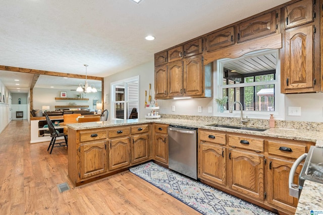 kitchen featuring a sink, appliances with stainless steel finishes, light wood-type flooring, a peninsula, and a notable chandelier
