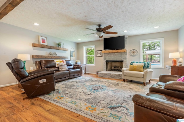 living area featuring baseboards, wood finished floors, a ceiling fan, and a textured ceiling