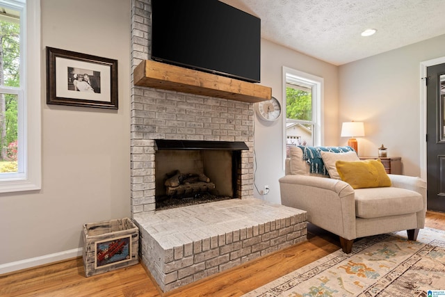 sitting room featuring a textured ceiling, baseboards, recessed lighting, a fireplace, and wood finished floors