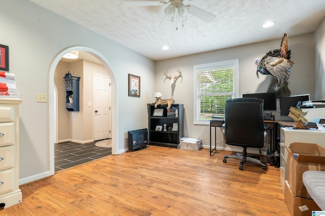 office featuring a textured ceiling, arched walkways, recessed lighting, wood finished floors, and a ceiling fan