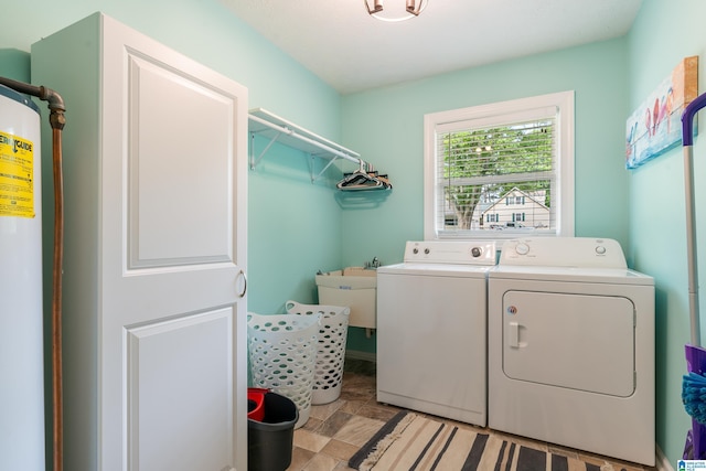 laundry area featuring stone finish floor, separate washer and dryer, laundry area, and a sink