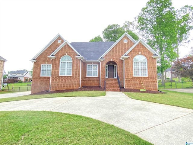 view of front of home featuring fence, brick siding, and a front lawn