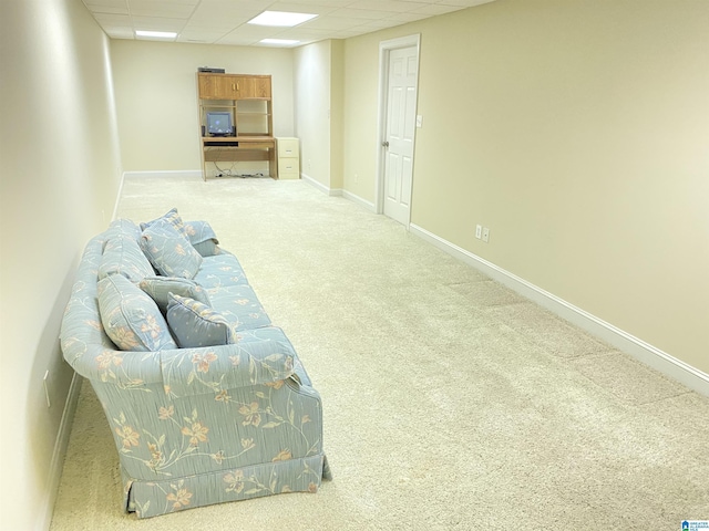 living area featuring a drop ceiling, carpet flooring, and baseboards