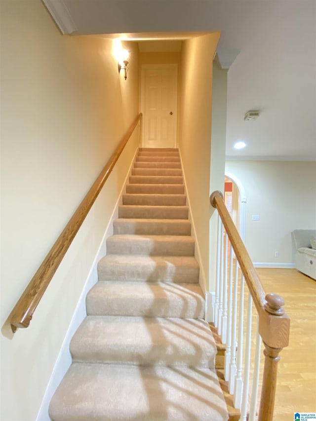 stairs featuring wood finished floors, recessed lighting, baseboards, and arched walkways