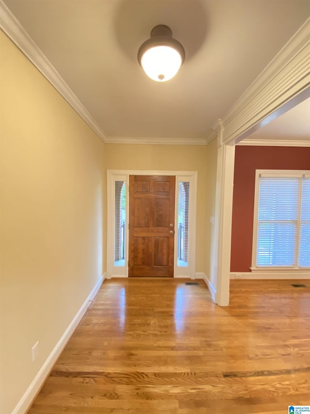 foyer with crown molding, wood finished floors, and baseboards