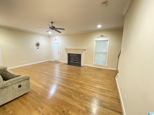 unfurnished living room featuring a fireplace with flush hearth, ceiling fan, light wood finished floors, and baseboards