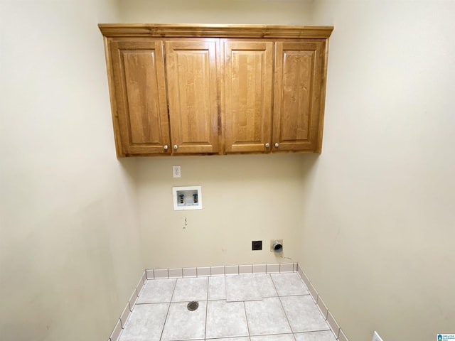clothes washing area with hookup for a washing machine, tile patterned floors, cabinet space, hookup for an electric dryer, and baseboards