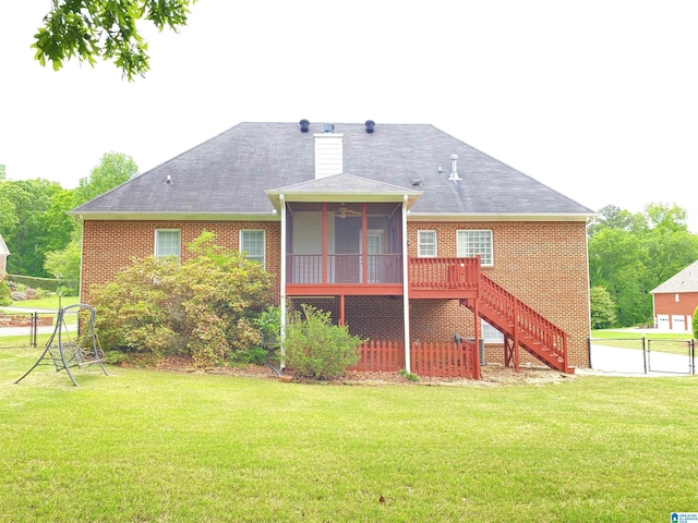 back of house with fence, stairway, a yard, brick siding, and a sunroom