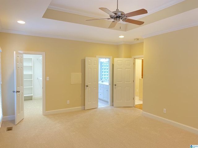 unfurnished bedroom with crown molding, light carpet, and a walk in closet