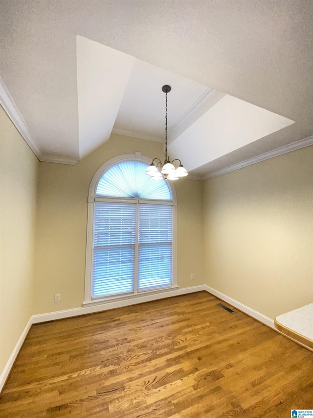 unfurnished dining area featuring wood finished floors, crown molding, vaulted ceiling, and baseboards