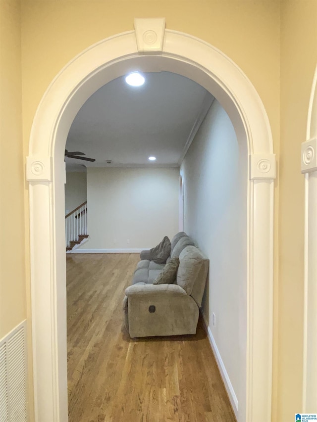 living area with visible vents, baseboards, arched walkways, wood finished floors, and stairs