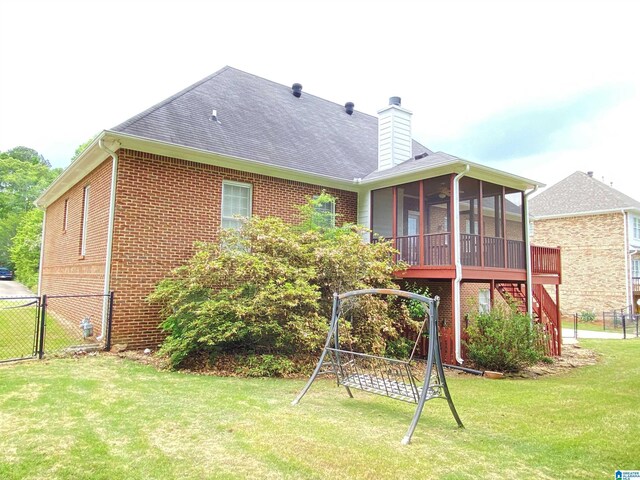back of property with fence, a chimney, a lawn, brick siding, and a sunroom