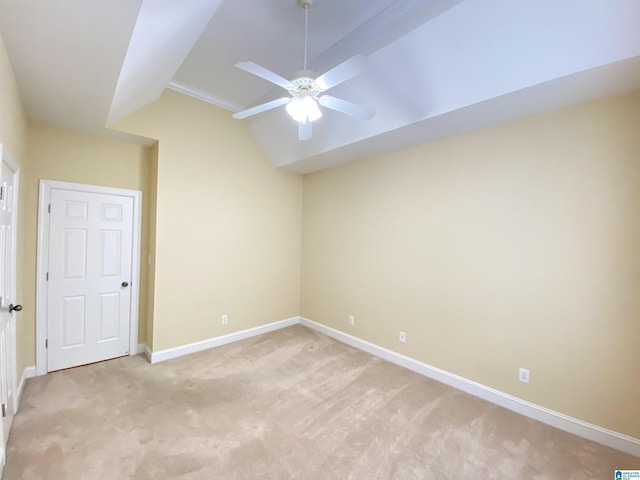 empty room with a ceiling fan, vaulted ceiling, light colored carpet, and baseboards