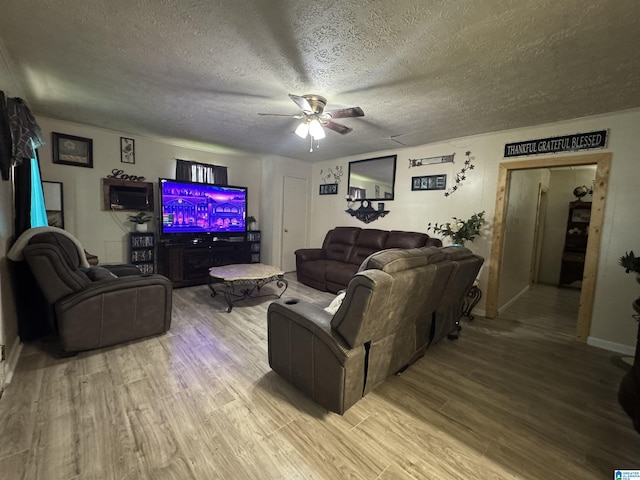 living area featuring a textured ceiling, wood finished floors, ceiling fan, and baseboards
