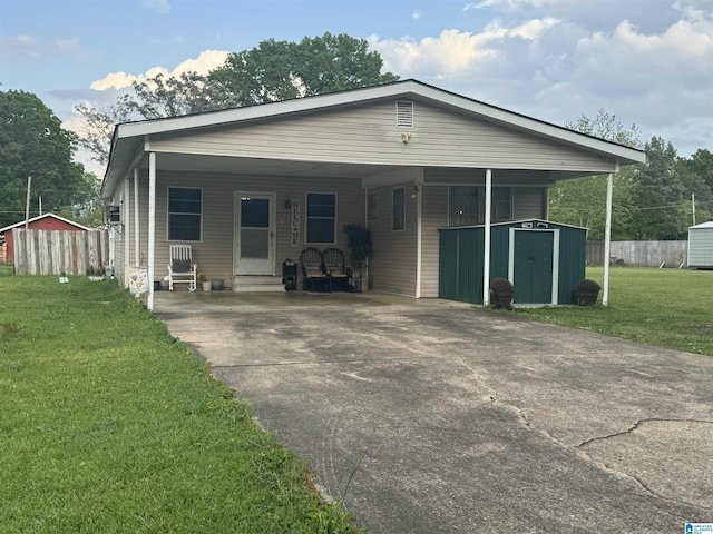 view of front of home featuring an outbuilding, an attached carport, a shed, a front yard, and concrete driveway