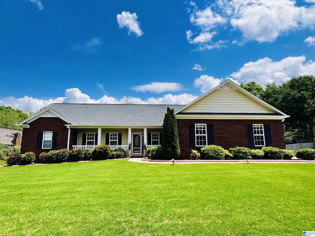single story home featuring covered porch, a front yard, and brick siding