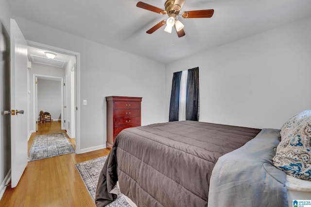 bedroom featuring baseboards, attic access, a ceiling fan, and light wood finished floors