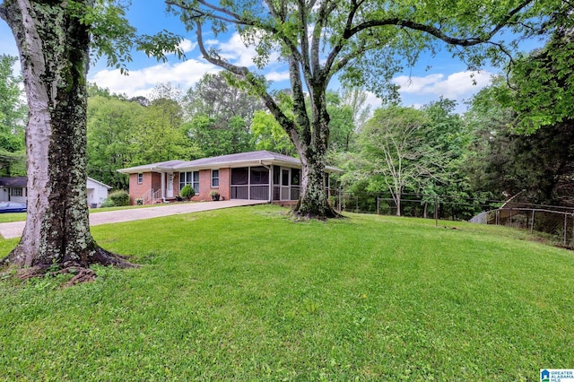 view of front of property featuring fence, a front lawn, driveway, and a sunroom