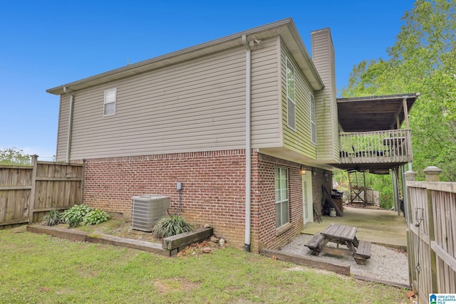 view of side of home featuring a patio area, brick siding, central AC, a chimney, and fence